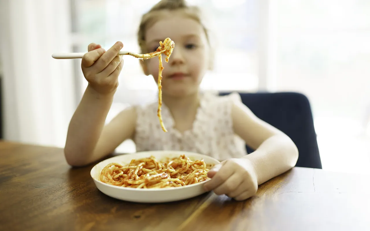 Tyttö syö spagettia.