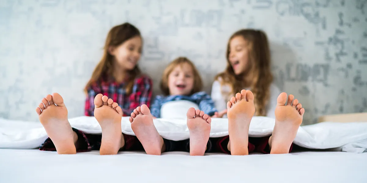 paljasjalkakengät lapselle: sisarukset makaavat sängyssä