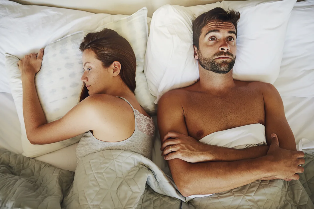Nainen ja mies makaavat sängyssä vihaisen näköisinä.